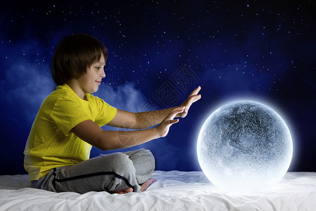 晚上梦可爱的男孩月亮星球坐床上图片