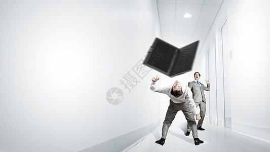 轻的商人试图逃避扔来的笔记本电脑两个商人互相争斗背景图片