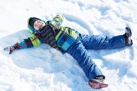 冬天的乐趣快乐的孩子躺冬天公园的雪地上图片