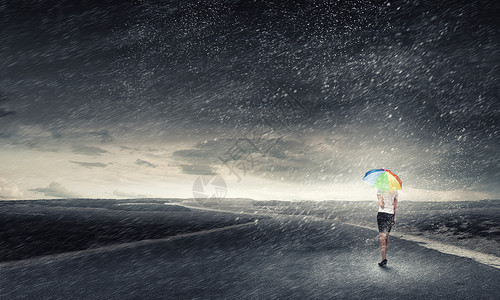 带彩虹伞的女人轻漂亮的女商人带着彩虹五颜六色的雨伞暴风雨中行走背景图片