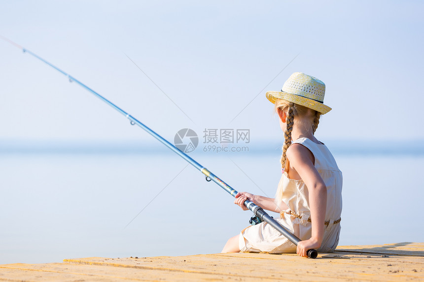 穿着连衣裙戴着钓鱼竿的帽子的女孩穿着连衣裙帽子的女孩带着钓鱼竿码头钓鱼图片