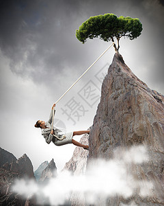 女商人爬山女商人攀登陡峭的山,树挂绳子上图片