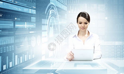 用现代技术的妇女女商人坐桌子上,用平板电脑与高科技蓝色背景图片