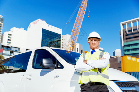 建筑工地的工程师建设者工程师建设者穿着安全背心建筑工地旁边的白色货车图片
