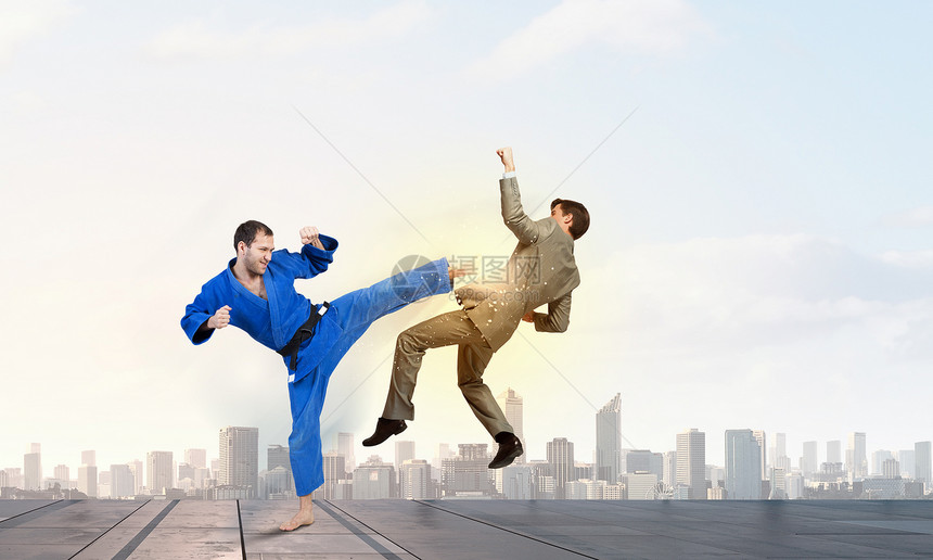 穿着蓝色基米诺的空手道男人轻坚定的空手道男子与西装革履的商人打架图片