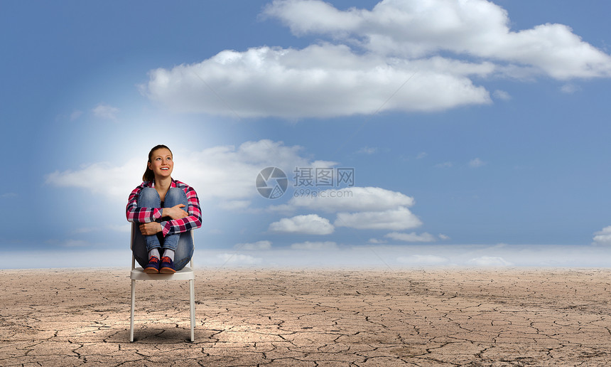 危机轻的女人坐沙漠中的椅子上图片