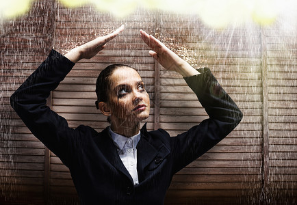 商业危机轻的女商人用手保护她的头下雨图片