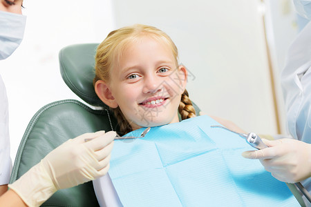牙齿检查可爱的微笑女孩坐扶手椅上看牙医背景图片