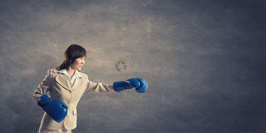 为成功而战轻自信的女商人戴着蓝色的拳击手套图片