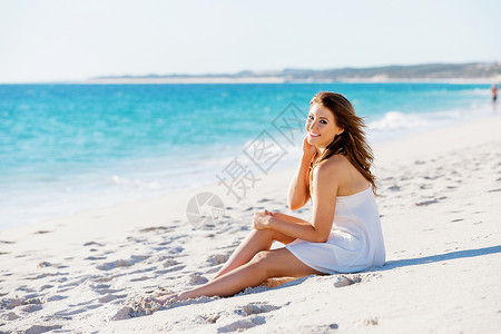 轻的女人坐海滩上坐海滩上的轻漂亮女人的肖像图片