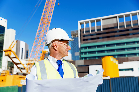 建筑工地的工程师建设者工程师建筑工人施工场景穿着带蓝图的安全背心图片