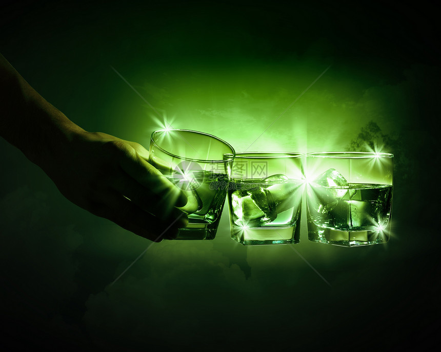 三杯带冰块的绿色腹肌手着三杯带着烟出的绿色苦艾酒中的杯图片