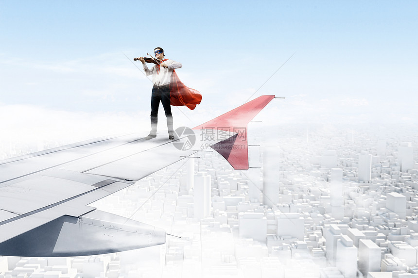 飞行飞机的机翼上轻的商人超级英雄飞机机翼边缘拉小提琴图片