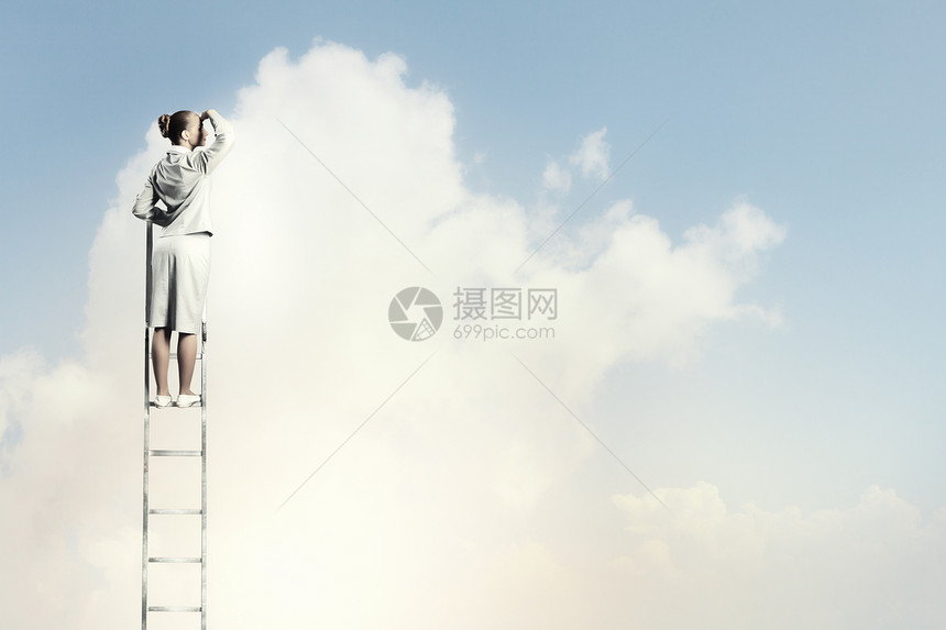 女商人站梯子上女商人站梯子上,多云的背景下眺望远方图片