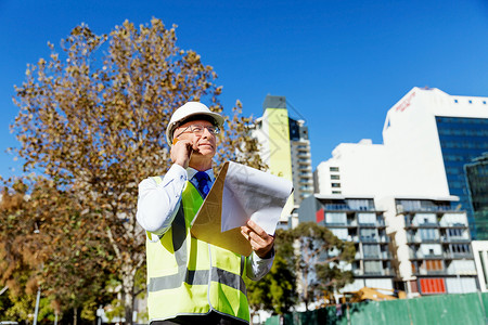 建筑工地的工程师建设者工程师建筑工人施工场景穿着安全背心记事本图片