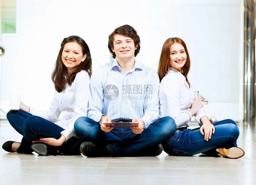 三个学生微笑着三个穿着休闲服的学生坐地板上微笑的形象图片