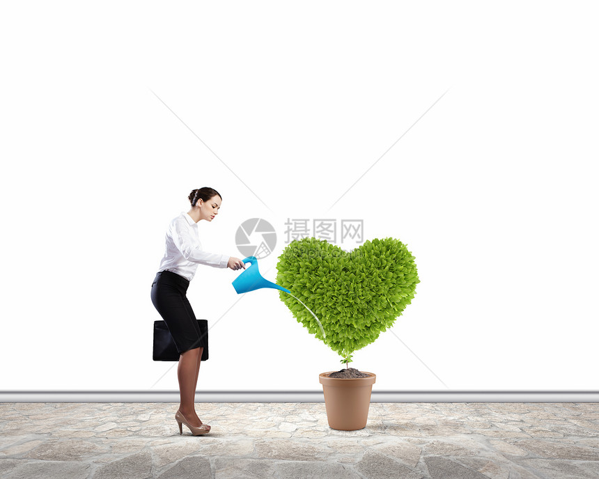 绿色植物轻吸引力的女商人用罐头锅里浇水图片