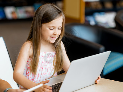 图书馆里着笔记本电脑的小女孩图书馆的技术乐趣背景图片