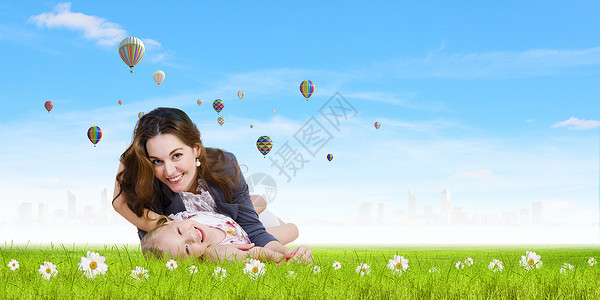 轻的家庭快乐的母亲女儿坐绿色的草地上图片