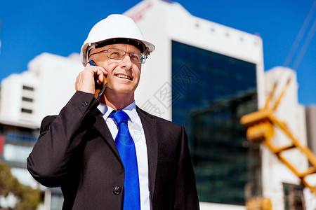 建筑工地的商人施工场景,司机戴着安全帽,带着手机图片