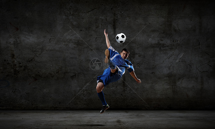 足球运动员足球运动员黑暗背景下踢球图片