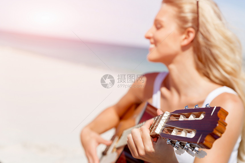 美丽的轻女人海滩上弹吉他美丽的轻微笑的女人海滩上弹吉他图片
