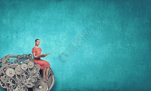 女人读书轻的女人穿着红色的衣服,手里着书,坐齿轮机构上图片