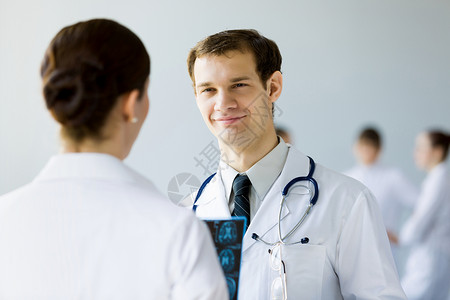 轻的男医生穿着白色制服的轻医生同事交谈图片