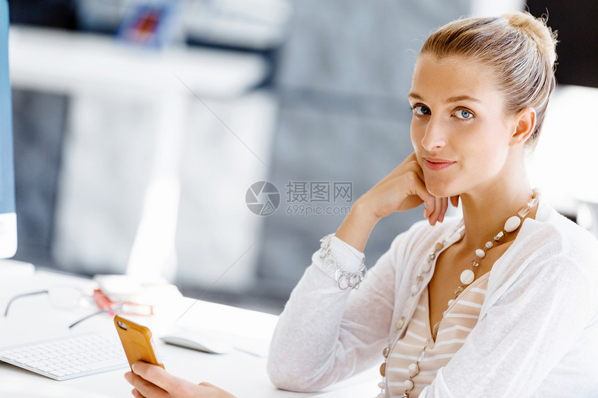 坐办公桌前的吸引力的上族魅力的女人坐办公室的桌子上着手机图片