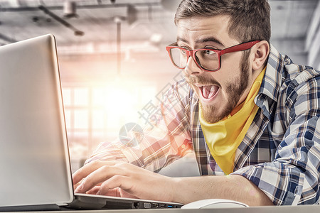 时髦的家伙用笔记本电脑戴着红色眼镜的轻情绪化的家伙上网图片