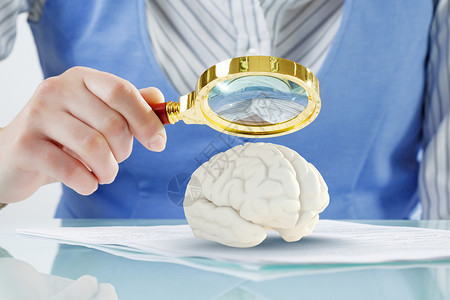大脑研究教育理念女用放大镜放大人脑的近景图片