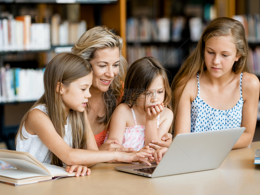 小女孩他们的妈妈图书馆里着笔记本电脑图书馆的技术乐趣图片