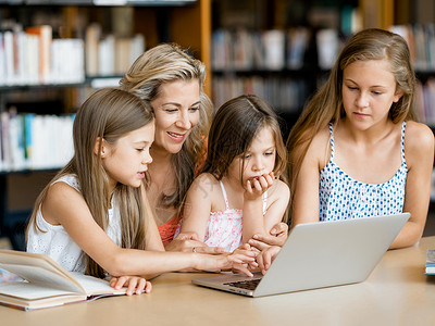 电子书籍小女孩他们的妈妈图书馆里着笔记本电脑图书馆的技术乐趣背景