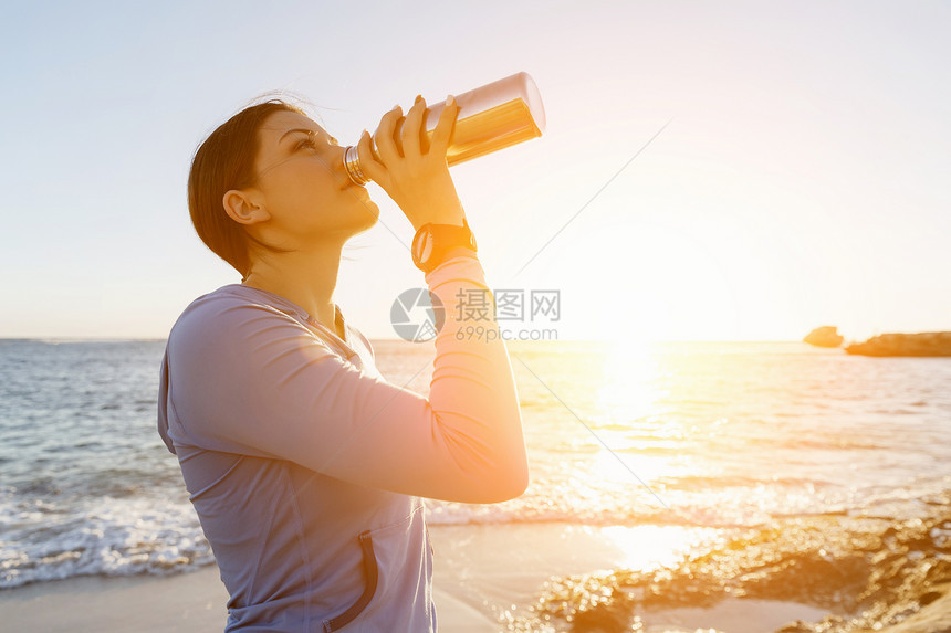 女人海滩上喝水轻女子海滩上锻炼后喝水图片