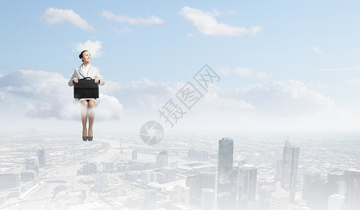 云上的女人轻漂亮的女商人坐城市上空的云端上图片