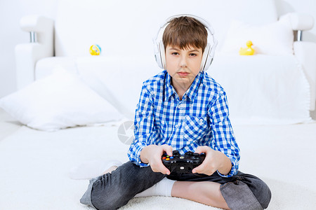 男孩玩游戏控制台情绪激动的男孩坐地板上玩游戏杆图片