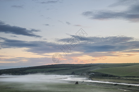 美丽的日出景观英国乡村,河流慢慢流过田野图片