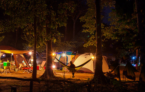 惊人的场景夜间露营女孩吊床上的帐篷背景图片