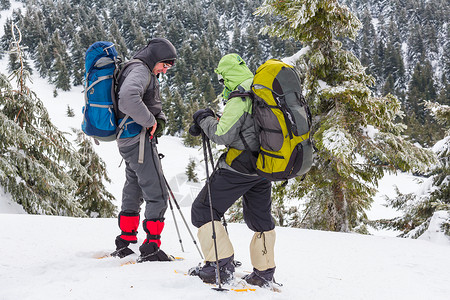 雪鞋冬天山上的徒步旅行者背景