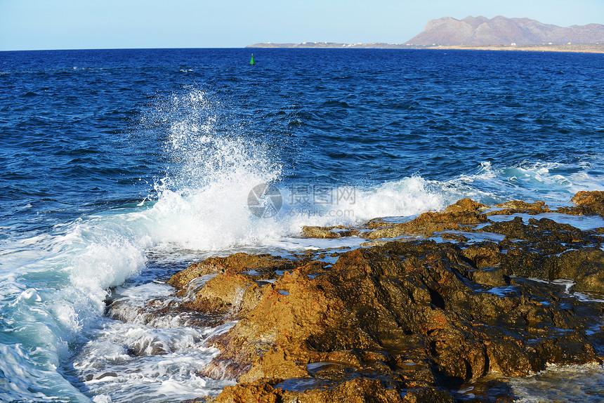 海浪溅岸边的石头上图片