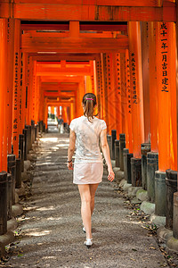 妇女走过木托里大门FushimiInari神社,京都,日本图片