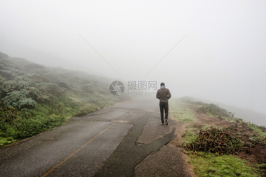 孤独的人穿过白雾沿着路走图片