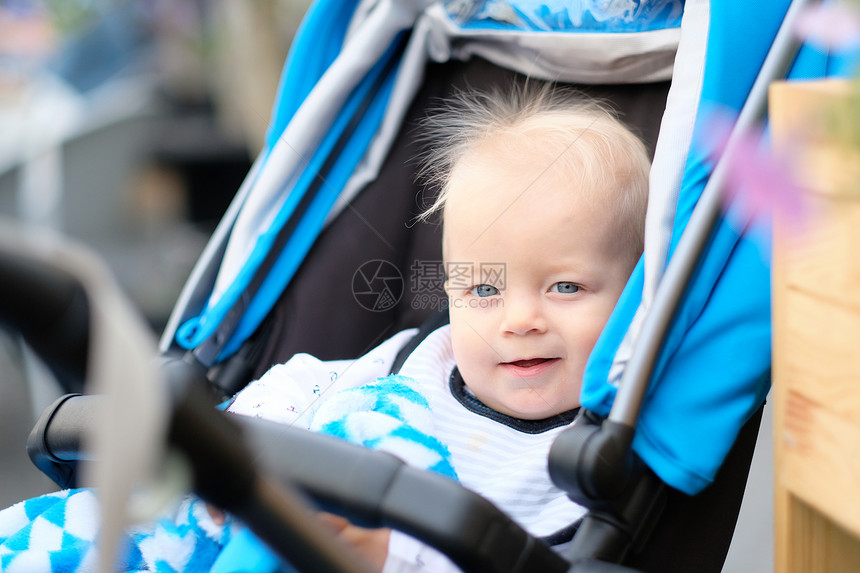 蓝眼睛的小男孩坐现代婴儿车里图片