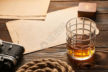 一杯威士忌和老式的测距仪相机木制背景图片