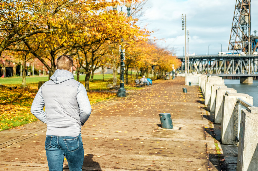 美国俄勒冈州的秋天,沿着波特兰市的河边散步的男人图片