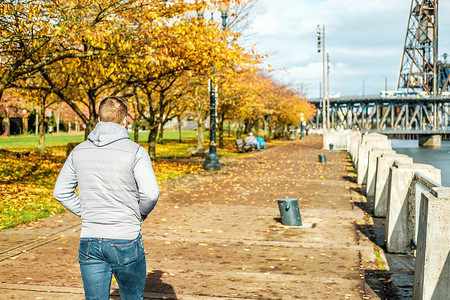 美国俄勒冈州的秋天,沿着波特兰市的河边散步的男人图片