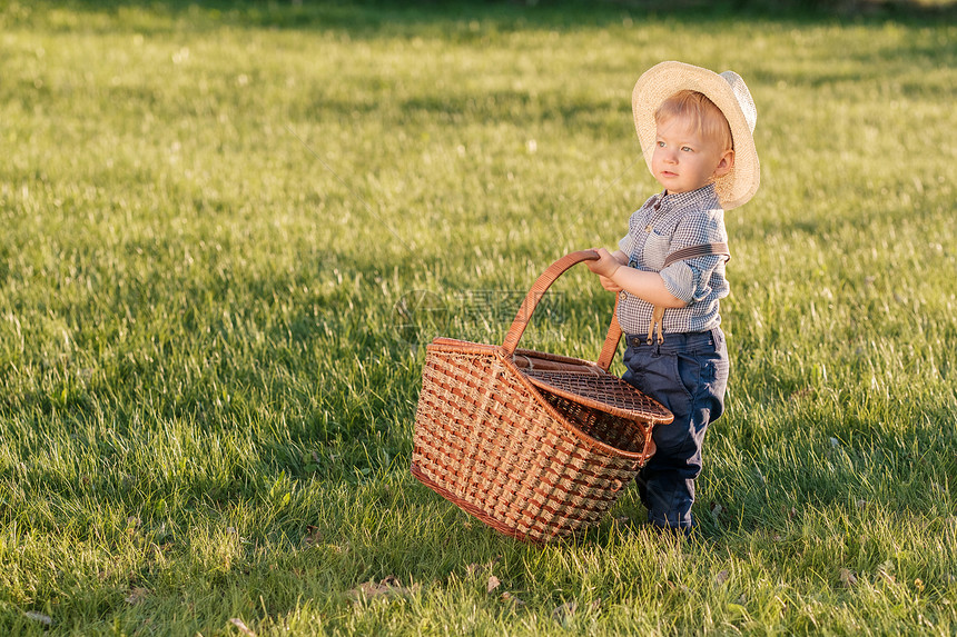 户外幼儿的肖像农村场景,岁的小男孩戴着草帽野餐篮图片