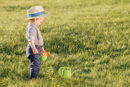 户外幼儿的肖像农村场景岁小男孩戴草帽用浇水罐高清图片