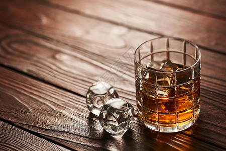 木立方体杯威士忌加冰块乡村木桌上,背景