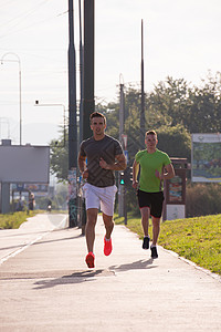 运动的轻人喜欢跑步,而太阳升城市上空图片